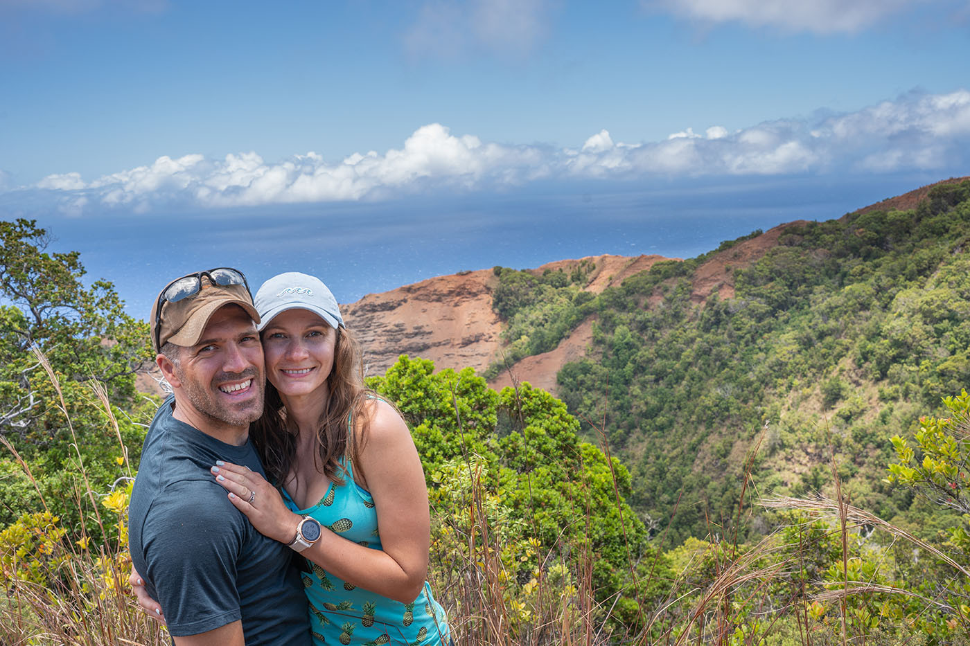 awaawapuhi-ocean-view-together.jpg Couple posing above a red ridge with the Pacific Ocean in the distance