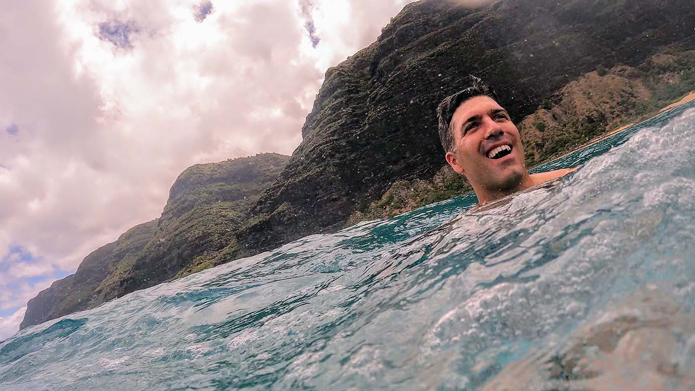 na-pali-coast-swim-2.jpg Swimmer smiling in the ocean beneath the steep Na Pali Coast cliffs