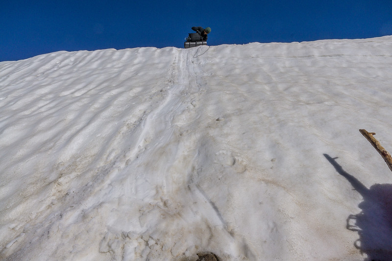 Backpack being lowered down the steep snow slope with 550 cord