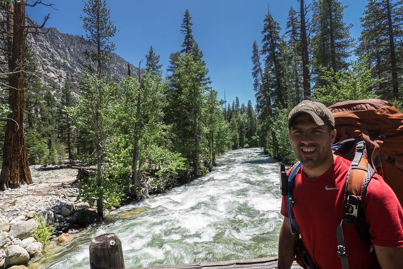Backpacker standing on the bridge over the rushing Kern River