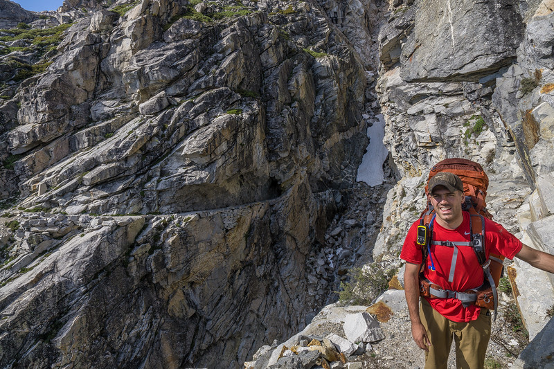 Backpacker on the far side of the snow chute above the granite ravine