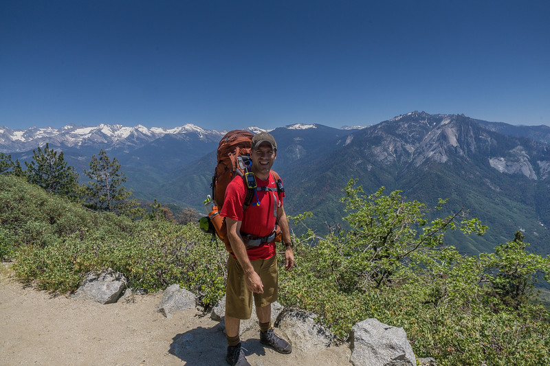 Backpacker on the High Sierra Trail overlooking the snowcapped Sierra Nevada