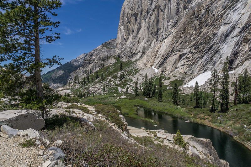 Small alpine lake beneath a sheer granite wall