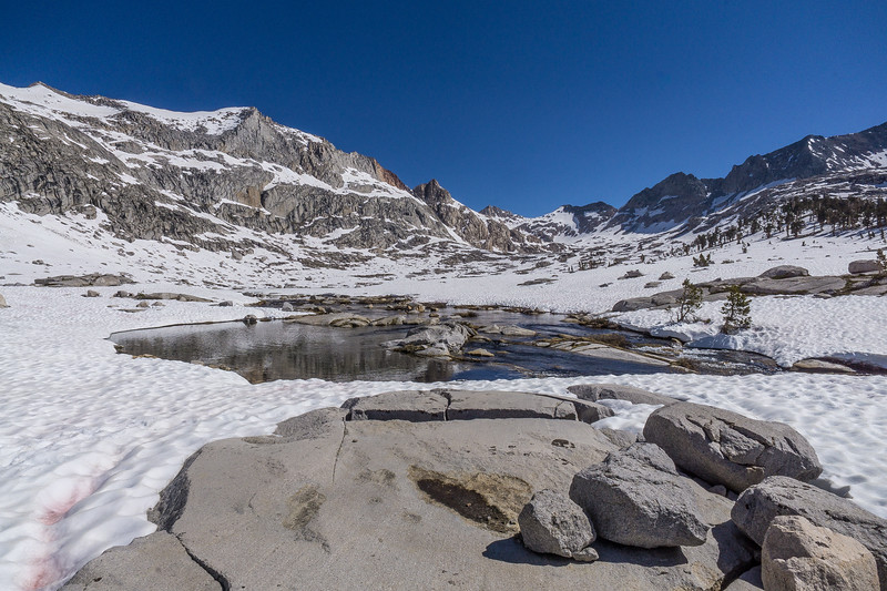 Partially frozen stream winding through the Big Arroyo snowfield