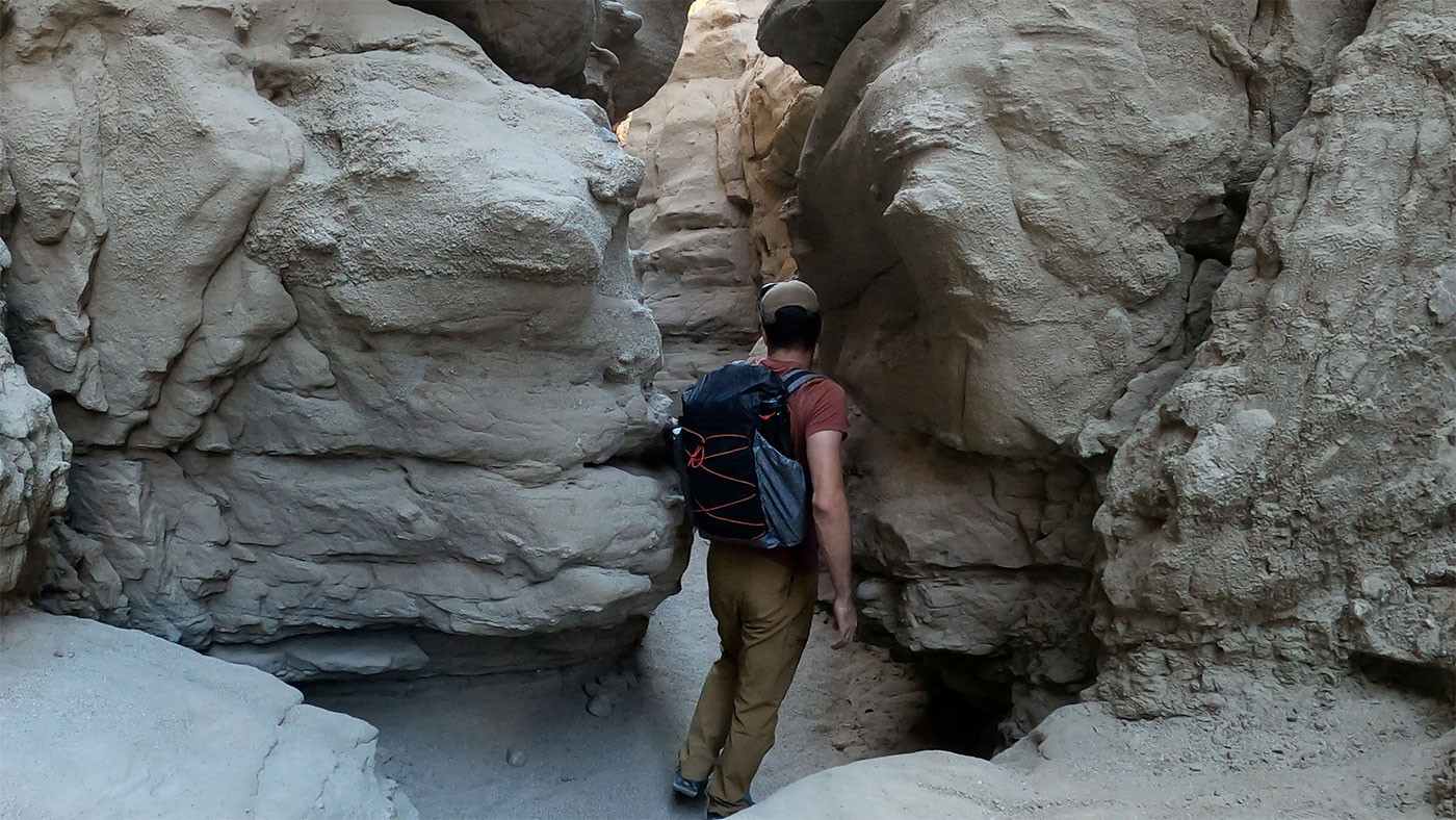 narrow-slot-canyon-1.jpg Hiker approaching a narrow passage between sculpted canyon walls