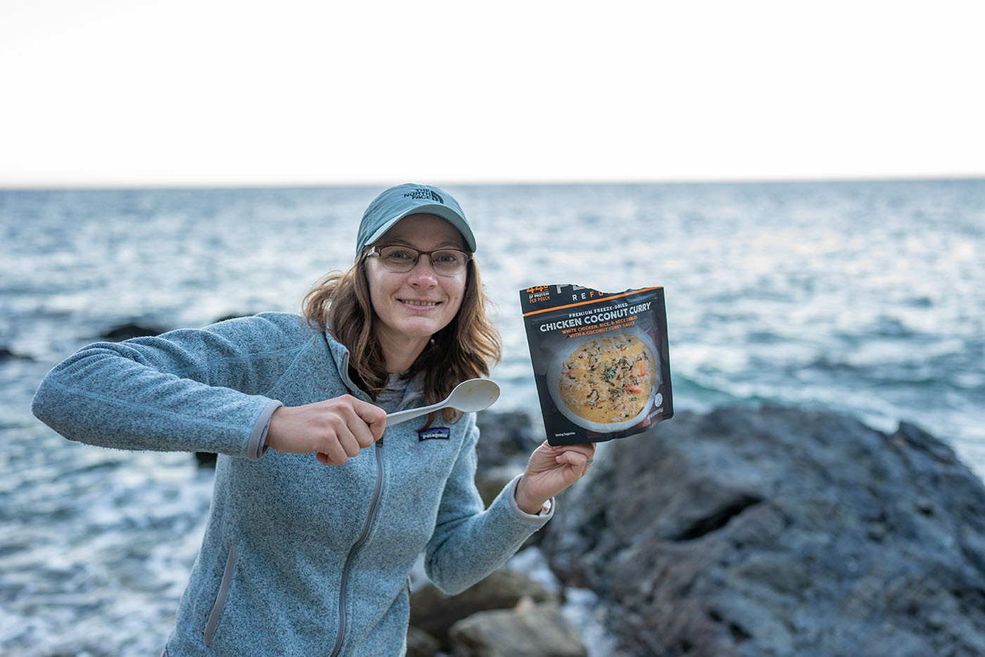 dinner-at-the-italian-gardens.jpg Camper holding a chicken coconut curry meal beside the ocean