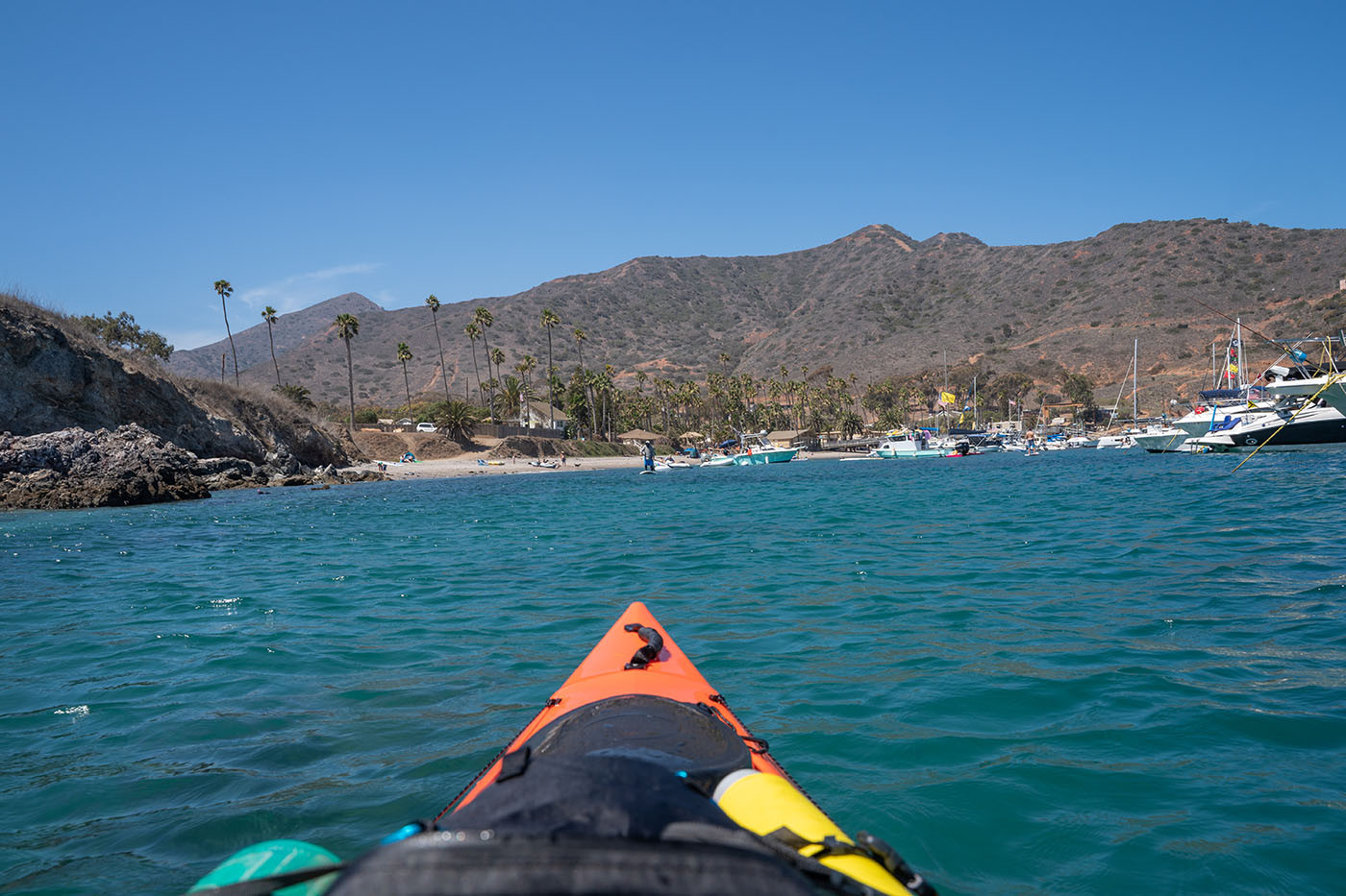 two-harbors-kayaking-in.jpg View from an orange kayak approaching the beach and marina at Two Harbors