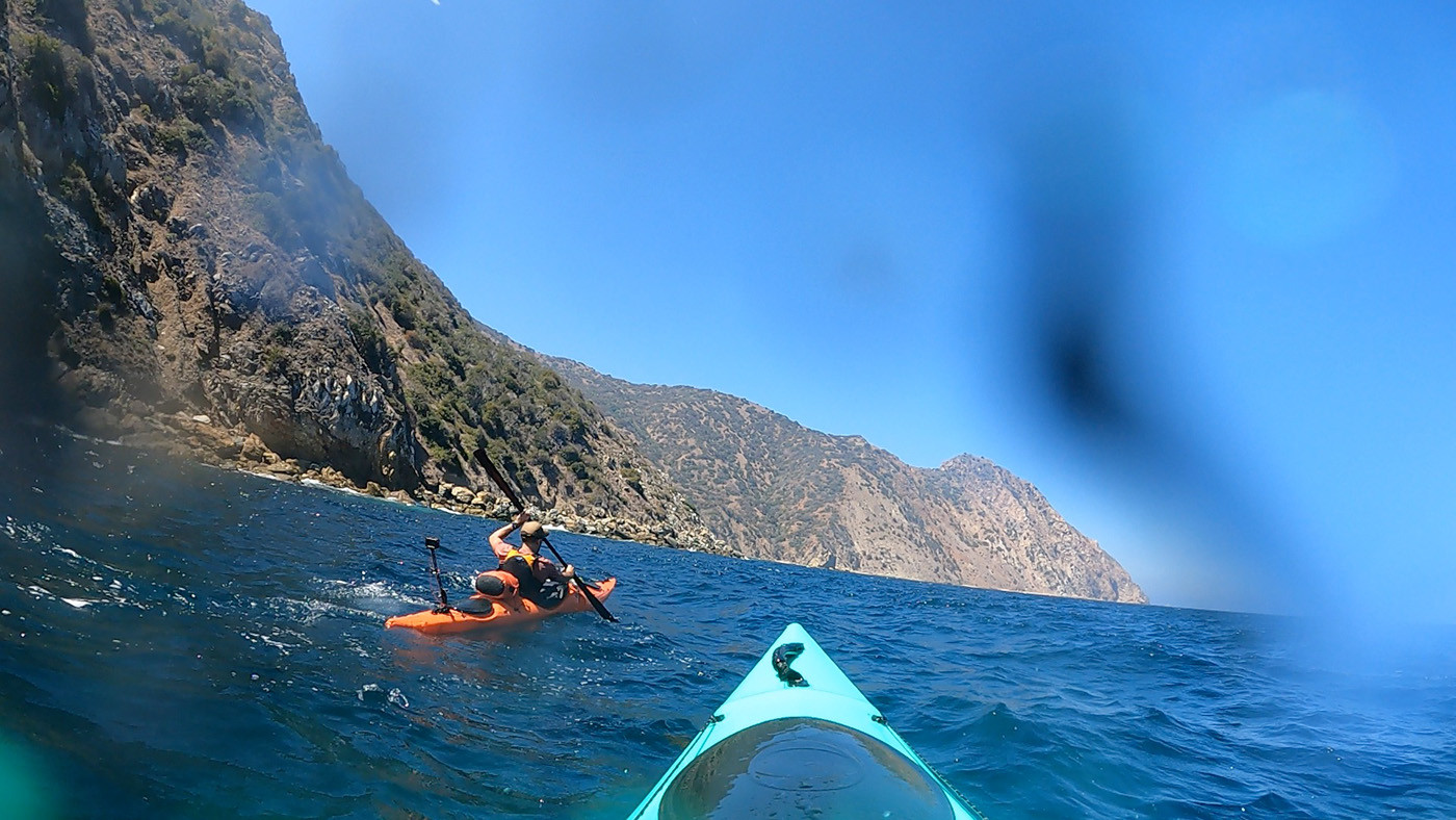 long-point-catlina-waves.jpg Orange and teal kayaks crossing choppy water near Long Point cliffs