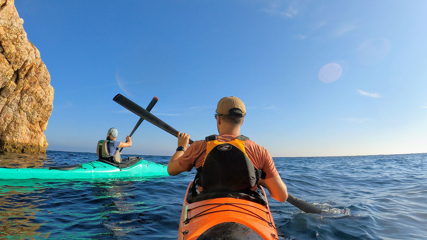 kayaking-catalina-island.jpg Two kayakers paddling close to a sunlit Catalina Island cliff