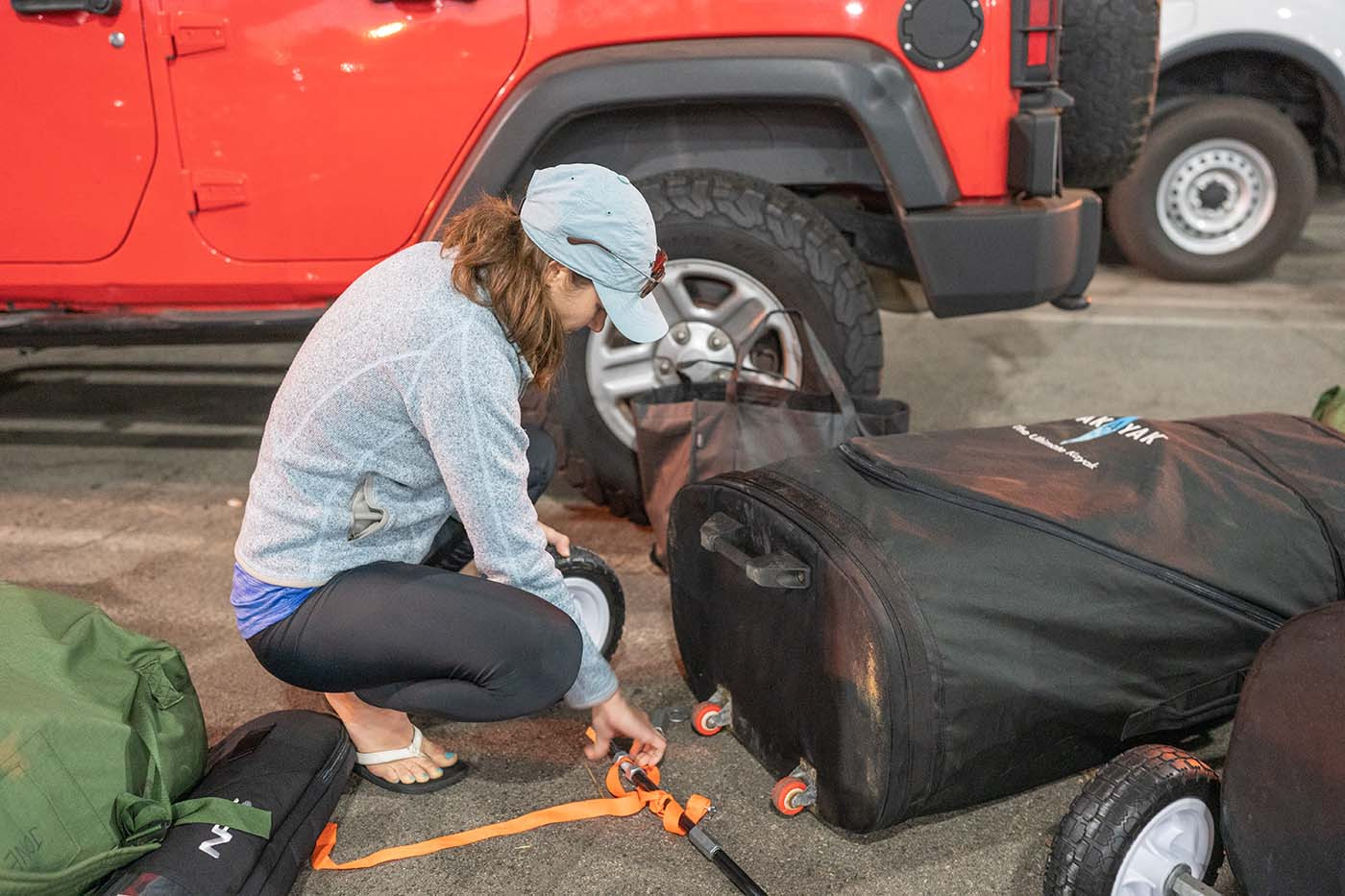 pakayak-custom-wheels.jpg Securing custom large wheels to a Pakayak travel bag beside a Jeep