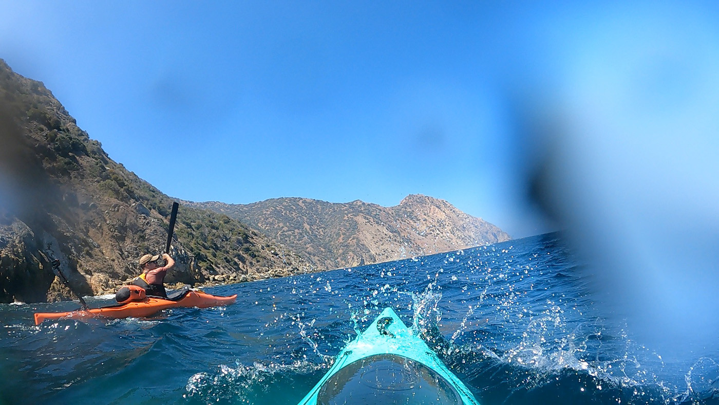 catalina-kayaking-long-point-1.jpg Sea spray breaking over a teal kayak beside an orange kayak near Long Point