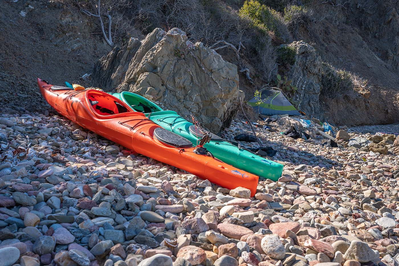 trans-kayak-catalina.jpg Orange and teal touring kayaks beside a tent on a rocky Catalina Island beach